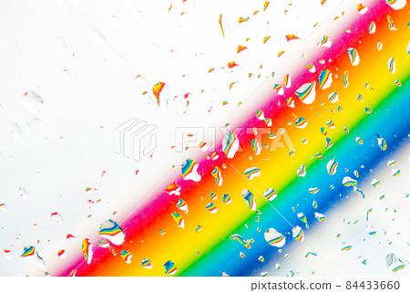 A rainbow behind a glass windows with water drops, Point of view, from behind the glass with drops. 84433660