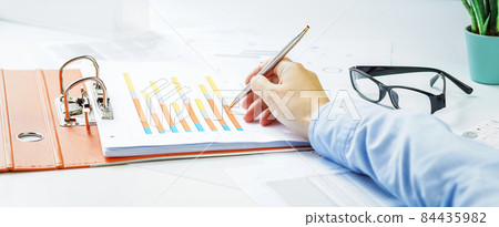 Finance. Female hand with calculator on financial graphs on desk 84435982
