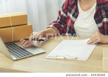 Woman checking stock goods supply delivery package shipping use document checklist. Asian woman startup small business at home office. Online entrepreneur asian woman use tablet checking online order 84436066