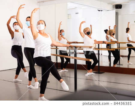 Group of multiethnic female dancers training in masks during COVID-19 pandemic 84436381