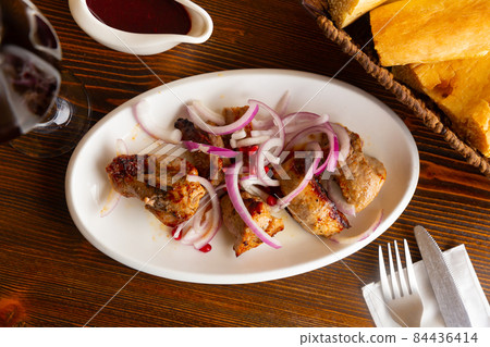 Grilled pork meat shashlik with marinated onion 84436414
