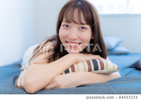 一個女人拿著墊子在床上微笑 一個女人拿著墊子在床上微笑 84437233