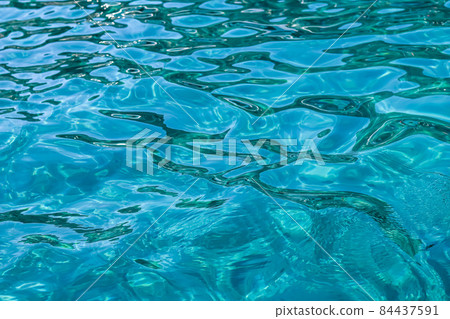 Turquoise sea waves in sunshine glow as surface background. Summer holidays and coastal nature concept 84437591