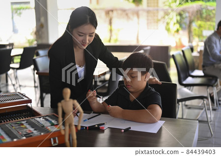 Asian teacher helping her student drawing in art class. 84439403