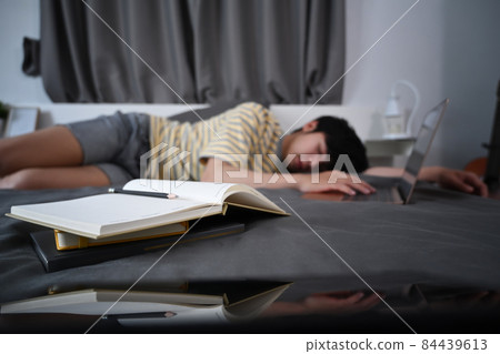 Tired asian man sleep on the bed with books at night. Tired asian man sleep on the bed with books at night. 84439613