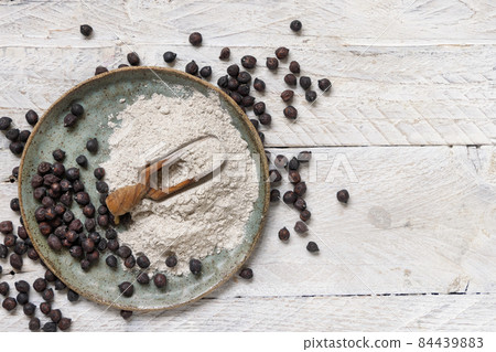 Plate and wooden scoop of black chickpea flour and beans top view Plate and wooden scoop of black chickpea flour and beans top view 84439883