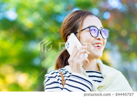 A smiling woman talking on a smartphone A smiling woman talking on a smartphone 84440787