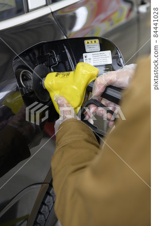 A person who refuels a car 84441028