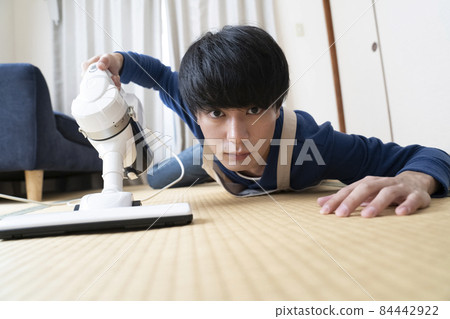 A man cleaning with a vacuum cleaner 84442922