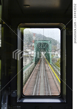 從雨中行駛的飯田線飛京站窗外眺望天龍川大橋 84443032