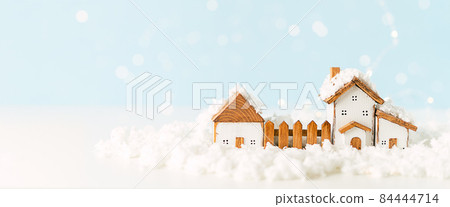 Happy New Year and Merry Christmas banner. Festive blue background with toy wooden house, snow, light bokeh, christmas tree, village and decoration. Copy space for winter holidays greeting card 84444714