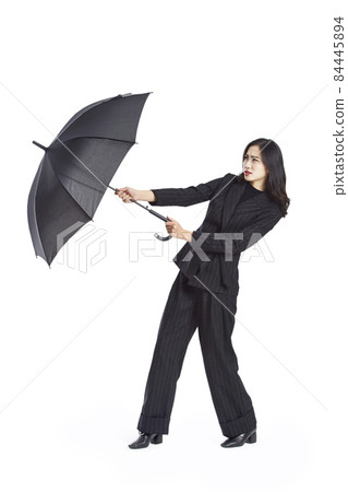 young asian businesswoman holding a black umbrella, studio shot, isolated on white background young asian businesswoman holding a black umbrella, studio shot, isolated on white background 84445894