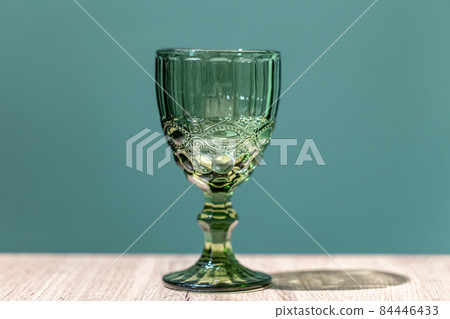 Glass green textured goblet on a blue background. Glass green textured goblet on a blue background. 84446433