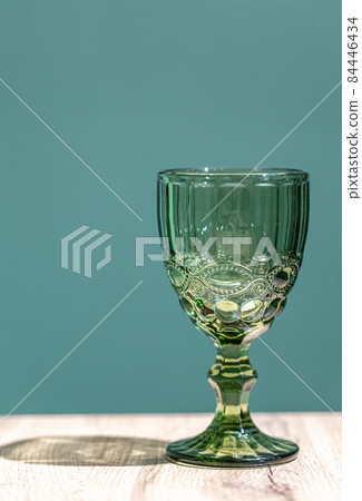 Glass green textured goblet on a blue background. Glass green textured goblet on a blue background. 84446434