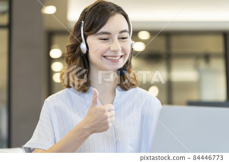 一個微笑的外國女人，她的拇指對著電腦屏幕舉起 84446773