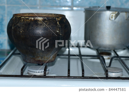 Antique cast iron and aluminum saucepan on the stove. Antique cast iron and aluminum saucepan on the stove. 84447581