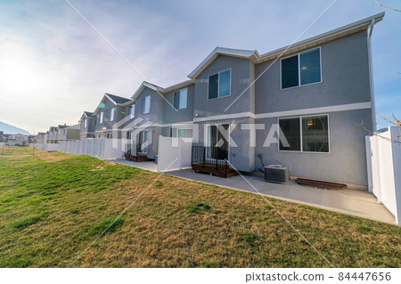 Large green field at the backyard of townhouses with sliding glass door and vinyl white fence 84447656