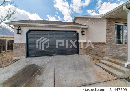 Clipped corner black sectional garage door exterior with a concrete driveway 84447709