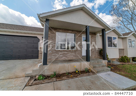 Exterior of a house with black garage door and stone veneer wall siding 84447710