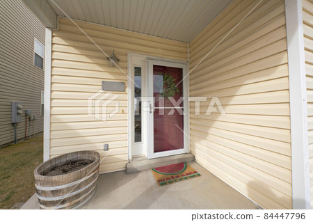 Exterior of a house entrance with a vinyl wood siding and a view of a lawn on the left 84447796