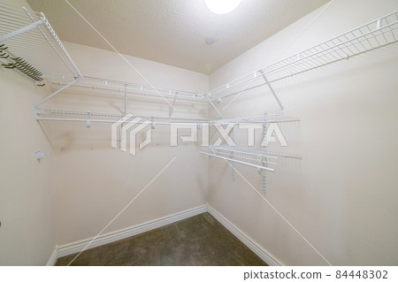 Interior of a windowless walk in closet with brown carpet flooring Interior of a windowless walk in closet with brown carpet flooring 84448302
