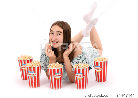 Girl lies on the floor with buckets of popcorn.. Isolated on white. Girl lies on the floor with buckets of popcorn.. Isolated on white. 84448444