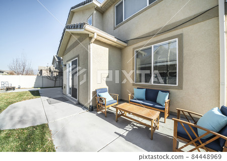 Patio outside a two-storey house with concrete flooring and green lawn Patio outside a two-storey house with concrete flooring and green lawn 84448969