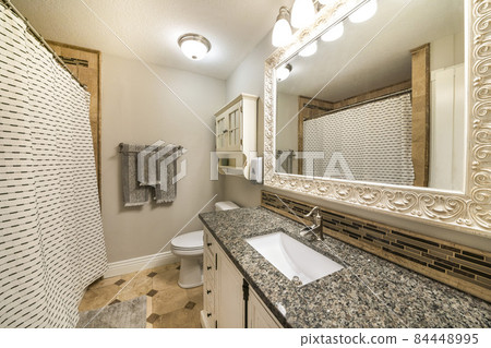 Traditional bathroom interior with limestone tiles and vanity unit with granite counter 84448995
