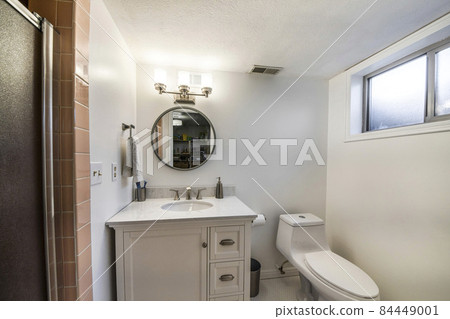 Bathroom interior with window, single vanity sink and one piece toilet bowl Bathroom interior with window, single vanity sink and one piece toilet bowl 84449001