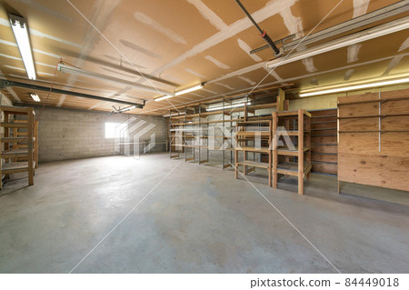 Unfinished garage interior with concrete blocks and a ceiling with white markings. Unfinished garage interior with concrete blocks and a ceiling with white markings. 84449018