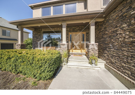 Front exterior of a two storey house with stone brick walls and shrubs at the front Front exterior of a two storey house with stone brick walls and shrubs at the front 84449075