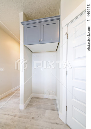 Empty refrigerator slot inside a house with built in gray wooden cabinet on top 84449458