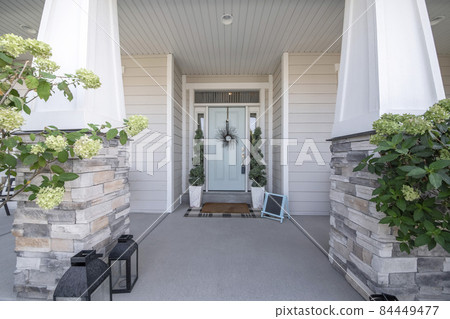 Entrance of a house with decorative light blue front door and posts with stone bricks Entrance of a house with decorative light blue front door and posts with stone bricks 84449477