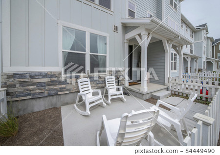 Patio in front of a townhouse with wooden white fence and rocking chairs Patio in front of a townhouse with wooden white fence and rocking chairs 84449490