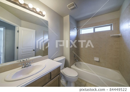 Bathroom interior with single vanity sink and bathtub shower unit with ceramic tiles surround Bathroom interior with single vanity sink and bathtub shower unit with ceramic tiles surround 84449522