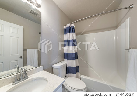 Bathroom interior with vanity sink and bathtub shower combo with striped shower curtain Bathroom interior with vanity sink and bathtub shower combo with striped shower curtain 84449527