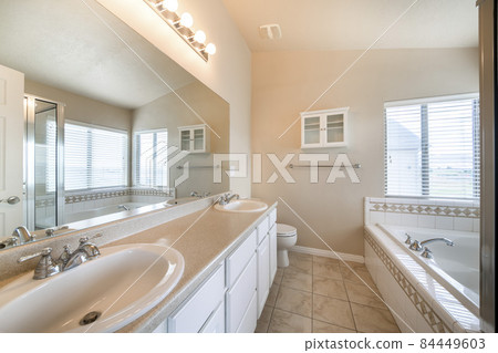 Spacious bathroom interior with windows and small wall cabinet on the front wall Spacious bathroom interior with windows and small wall cabinet on the front wall 84449603