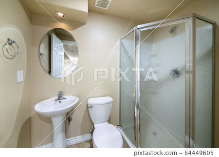 Small bathroom interior with sink, toilet and half hexagon shower enclosure with matted glass panel Small bathroom interior with sink, toilet and half hexagon shower enclosure with matted glass panel 84449605