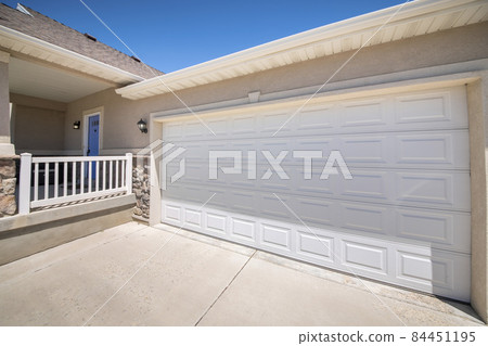 Front exterior of a garage with closed white panel door 84451195