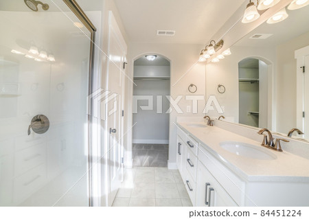 Interior of a white bathroom with shower with glass wall, sink and empty closet 84451224