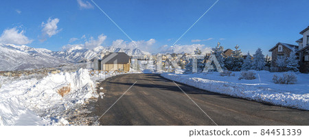 Snowy town with houses at Draper, Utah with snow plowed road and a view of Wasatch mountains 84451339