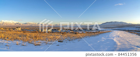 Vast field of snow with large houses at Saratoga Springs, Utah with view of Wasatch Mountains 84451356