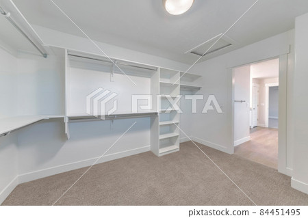 Walk in closet with built in shelves and two levels rods for clothes storage Walk in closet with built in shelves and two levels rods for clothes storage 84451495