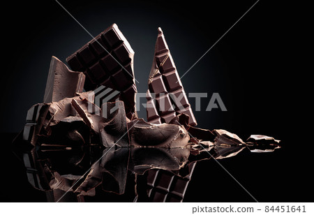 Black chocolate on a black reflective background. Black chocolate on a black reflective background. 84451641