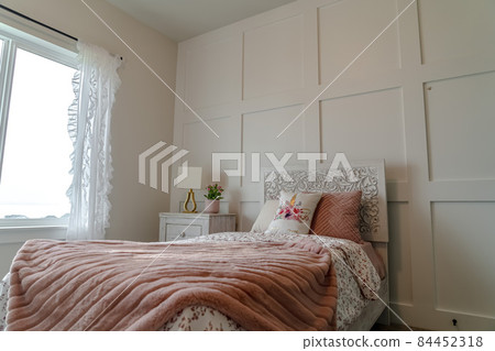 Single bed with decorative headboard and feminine blankets inside a home bedroom 84452318