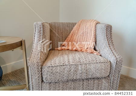 Armchair and round wood table inside a room with white wall and carpet on floor Armchair and round wood table inside a room with white wall and carpet on floor 84452331