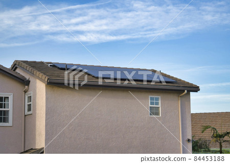 Solar panels on the pitched roof of a house with clouds and blue sky background Solar panels on the pitched roof of a house with clouds and blue sky background 84453188