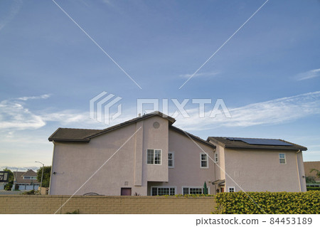 Two storey house exterior with beige wall and solar panels on the pitched roof Two storey house exterior with beige wall and solar panels on the pitched roof 84453189