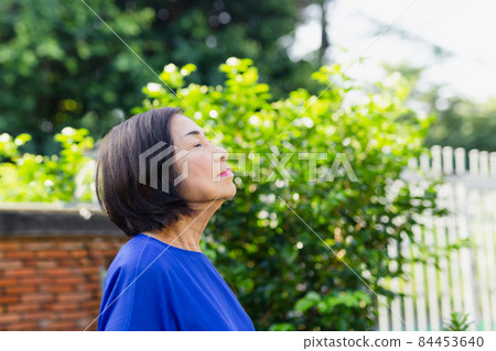 Portrait of senior woman relaxing and breathing fresh air in the garden outdoor. Portrait of senior woman relaxing and breathing fresh air in the garden outdoor. 84453640