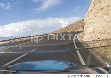 Driving on a curved uphill road beside a rocky mountain in Hurricane, Utah 84454001
